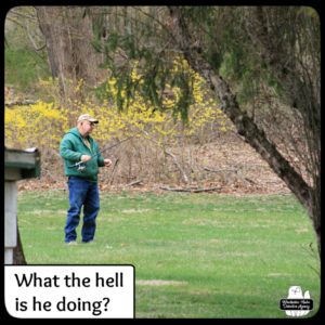 man with fishing pole in the grass; What the hell is he doing?