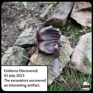 artifact on top of rocks; it's a broken set of metal hands opened with a bird on one thumb