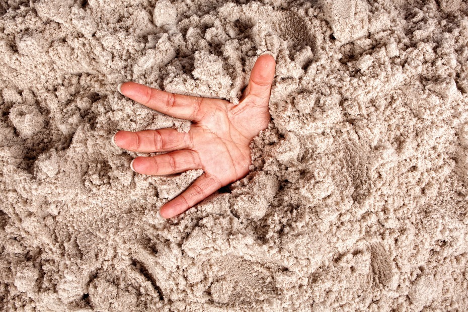 stock image: a hand reaching out from sand