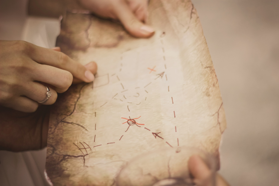 stock image of a woman's hands grazing over spots on a parchment paper treasure map