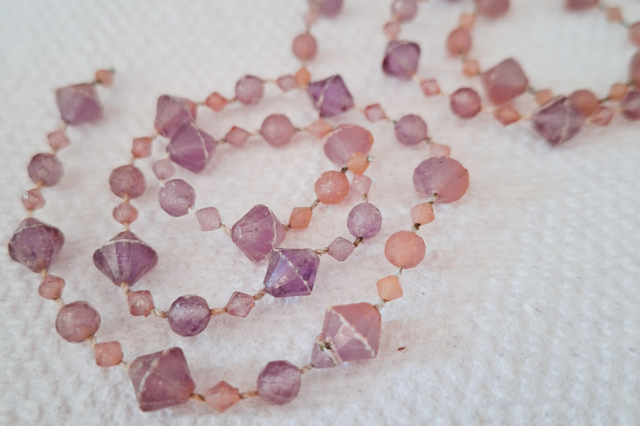 two strings of (plastic) purplish-pink gems in spirals on a white paper towel