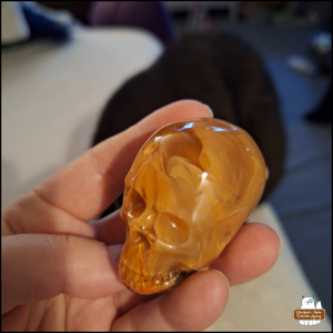 Amber's hand holding a medium resin flaming skull with black cat Gus in the background.