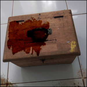 a Canva stock photo of an old wooden box with additional photo editing to make it and the white tiled floor look dirtier and more stained.