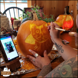 artist Meg Cocho carving Gus as a vampire into a pumpkin, 2023