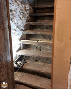 the old wooden stairs built over stones and dirt illuminated by a small lamp